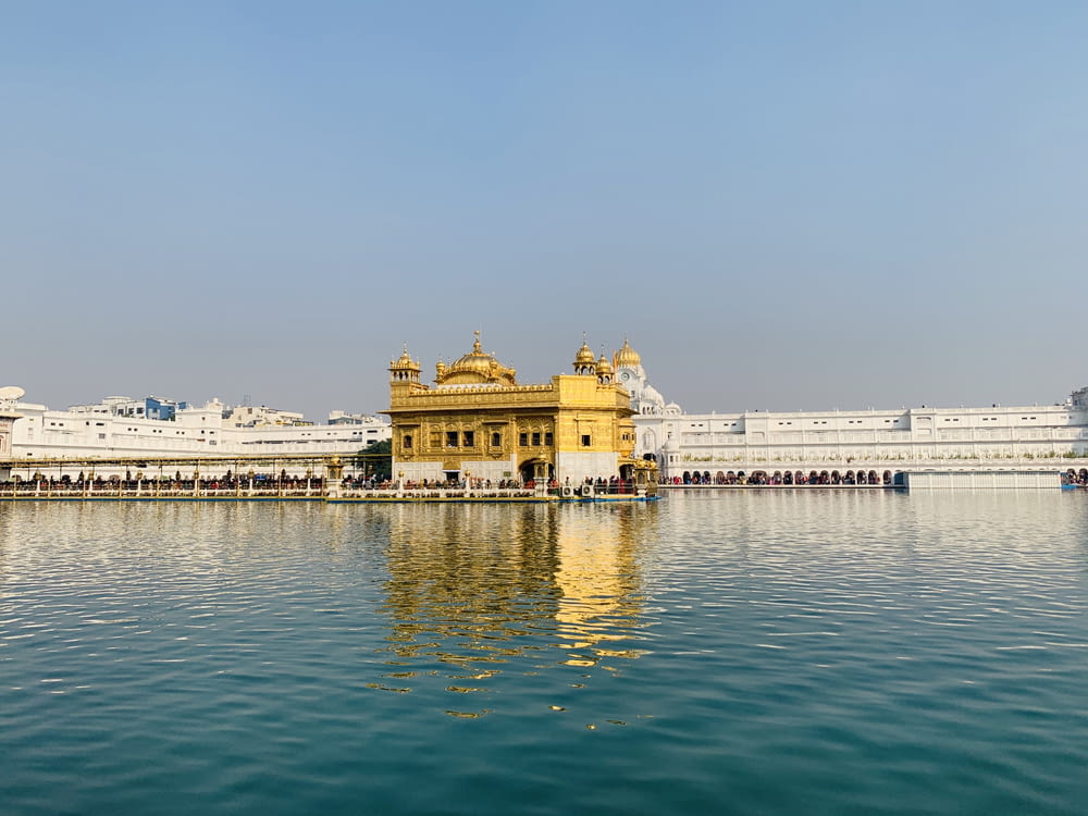 a body of water with buildings along it with Harmandir Sahib in the background