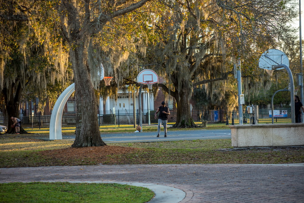 a man is playing basketball in a park