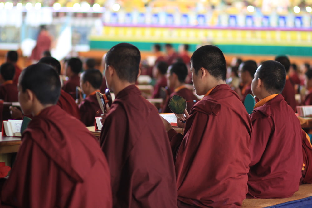 a group of monks sitting at desks in a room