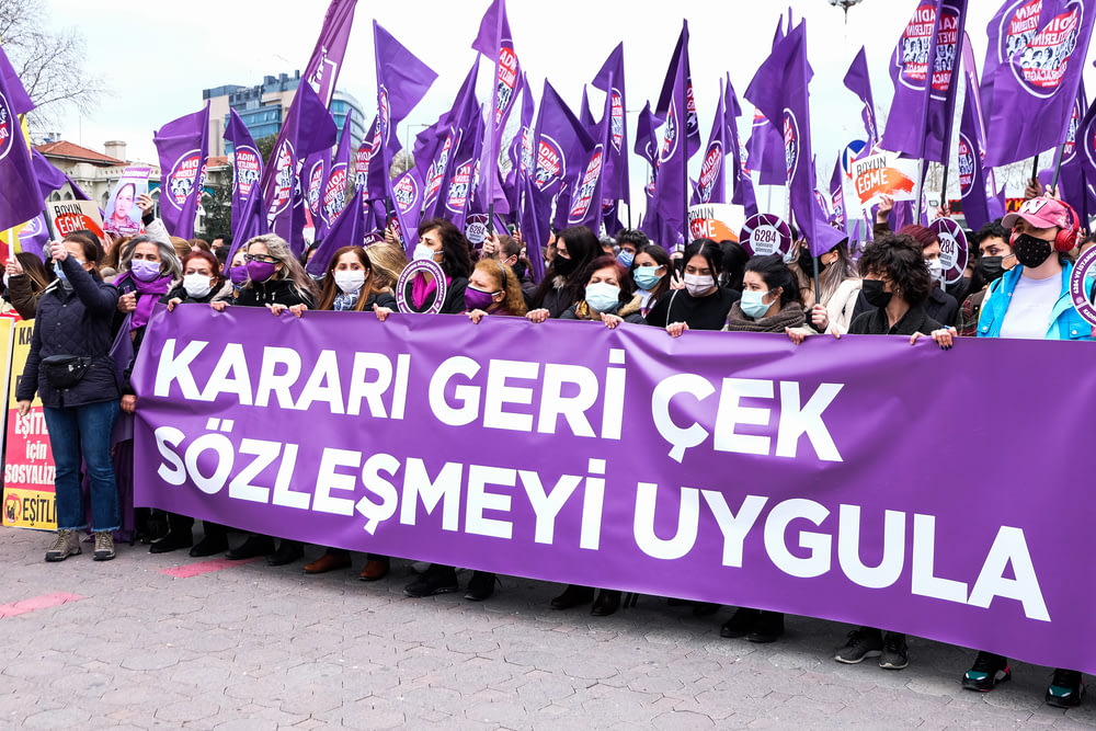 a large group of people holding a purple banner