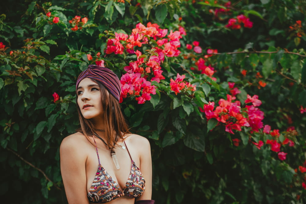a woman in a bikini standing in front of flowers