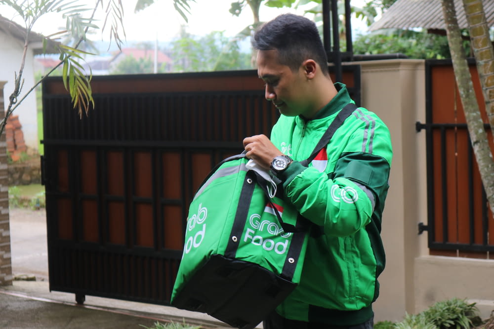 a man in a green jacket carrying a green bag