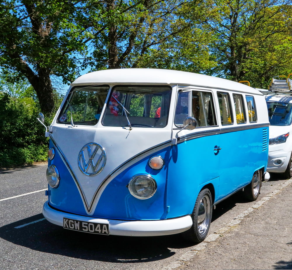 a blue and white vw bus parked on the side of the road