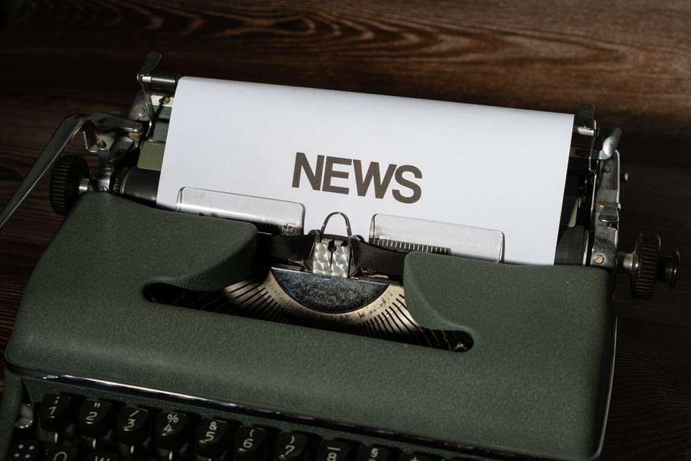 a close up of a typewriter with news paper on it