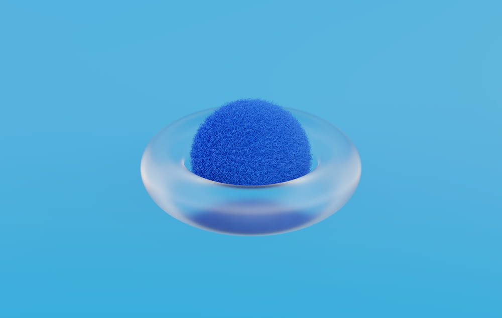 a blue sponge in a glass bowl on a blue background
