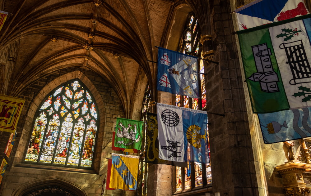 a cathedral with stained glass windows and banners hanging from the ceiling