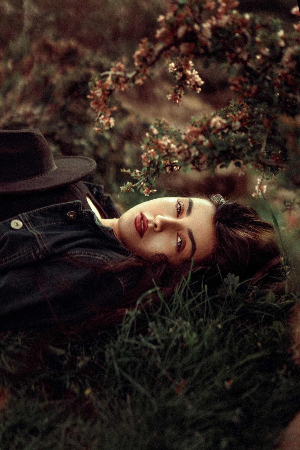 uma mulher deitada na grama com um chapéu na cabeça