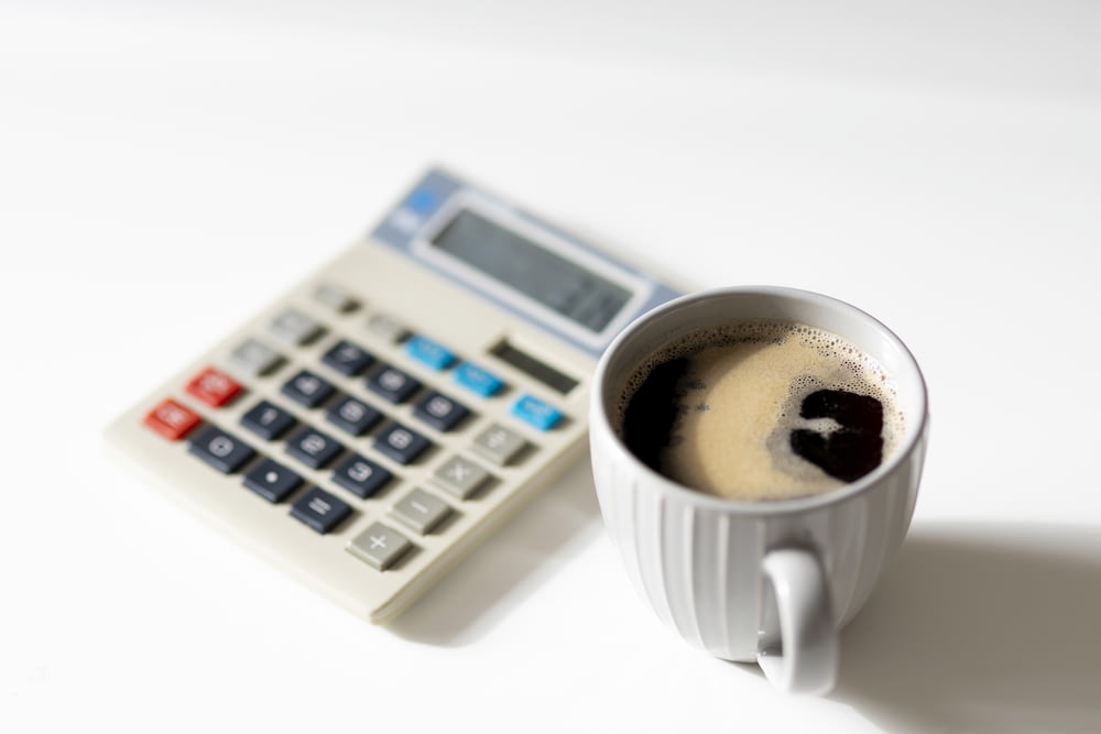 uma xícara de café ao lado de uma calculadora