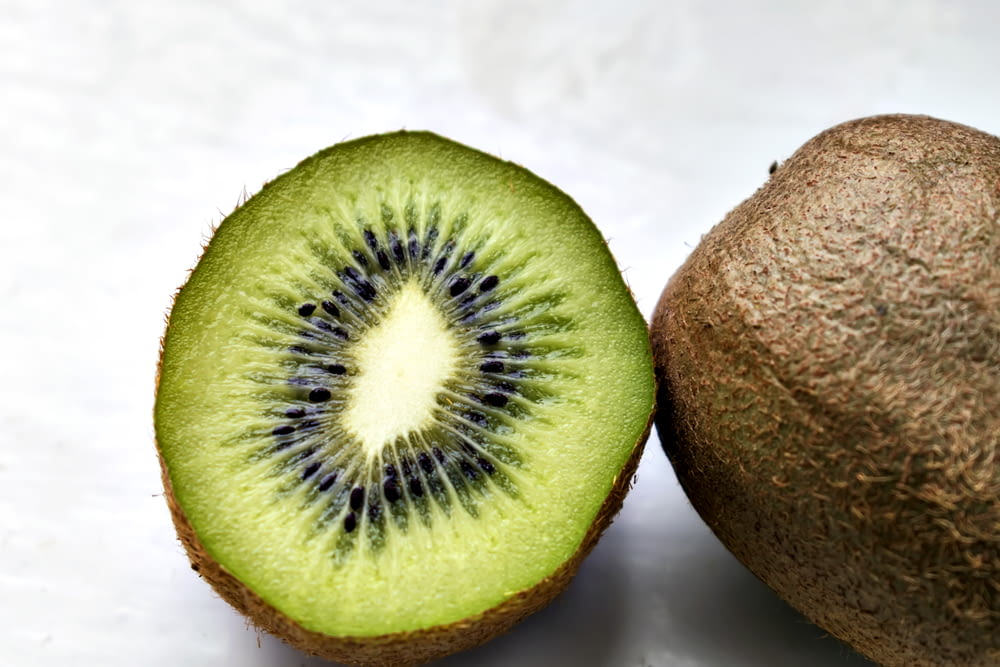 a kiwi fruit cut in half on a white surface