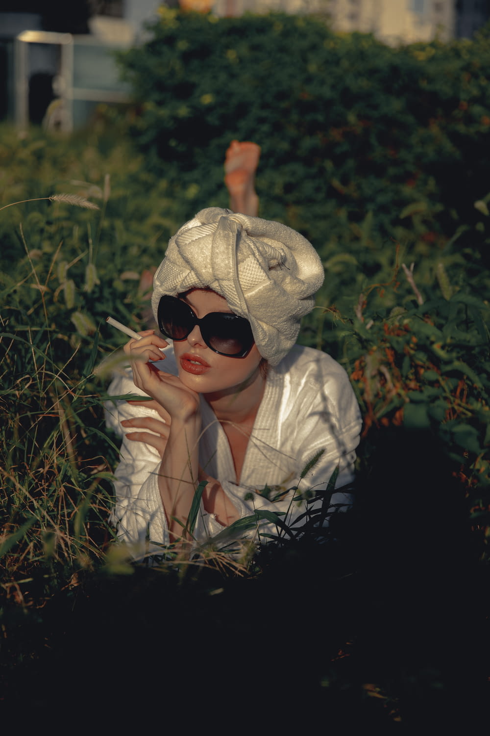 a woman in a white hat and sunglasses smoking a cigarette