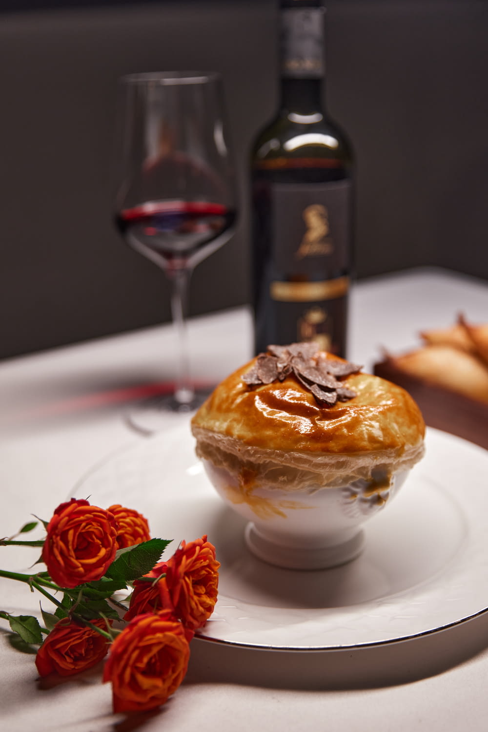 a white plate topped with a pie next to a bottle of wine