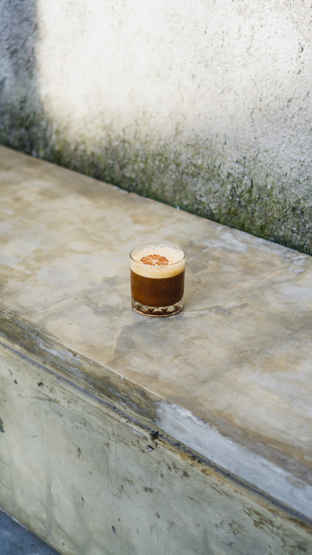 a cup of coffee sitting on top of a cement bench