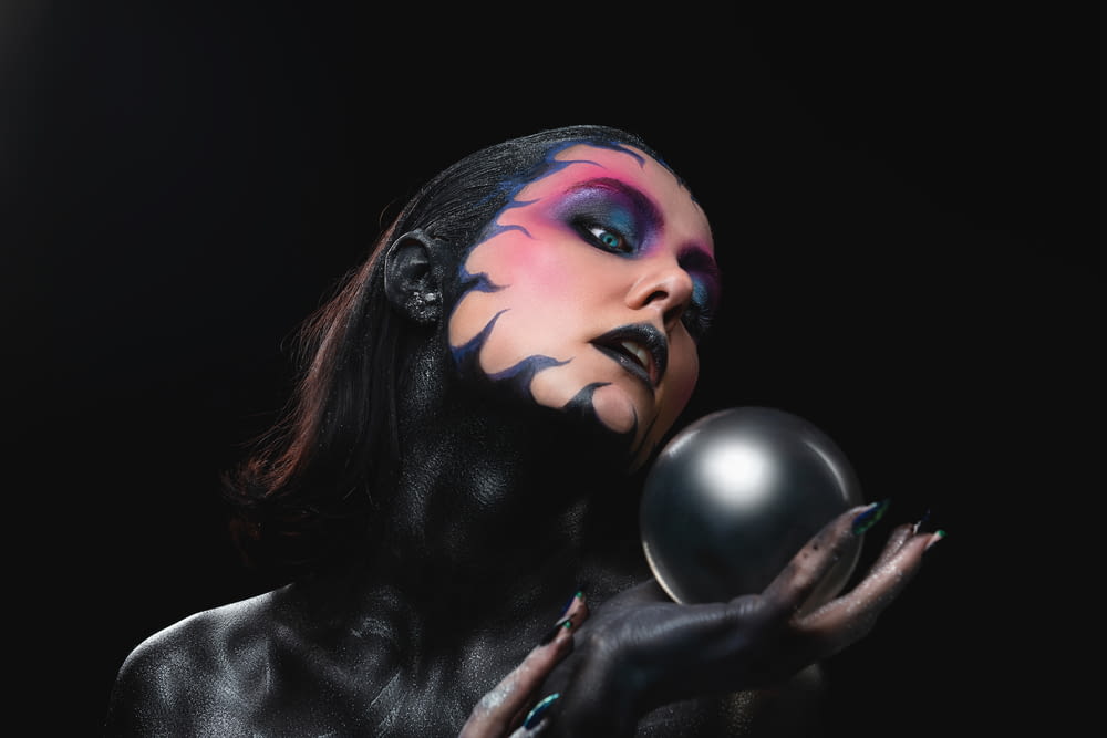a woman with black makeup holding a ball