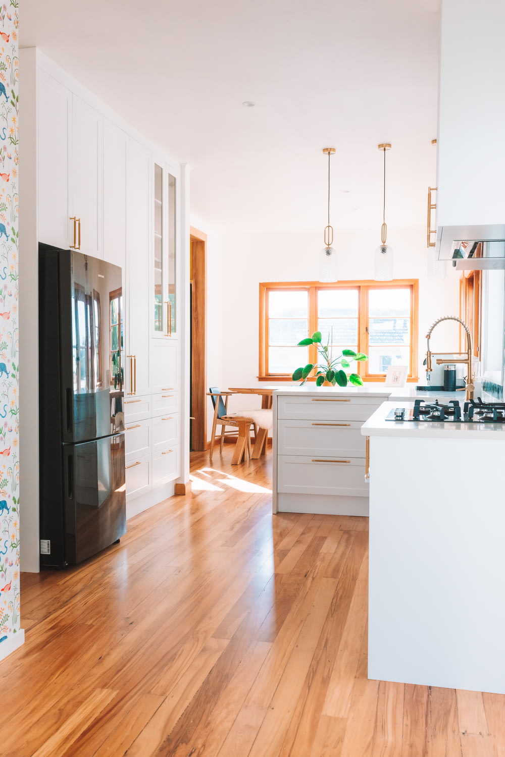 uma cozinha com pisos de madeira e armários brancos