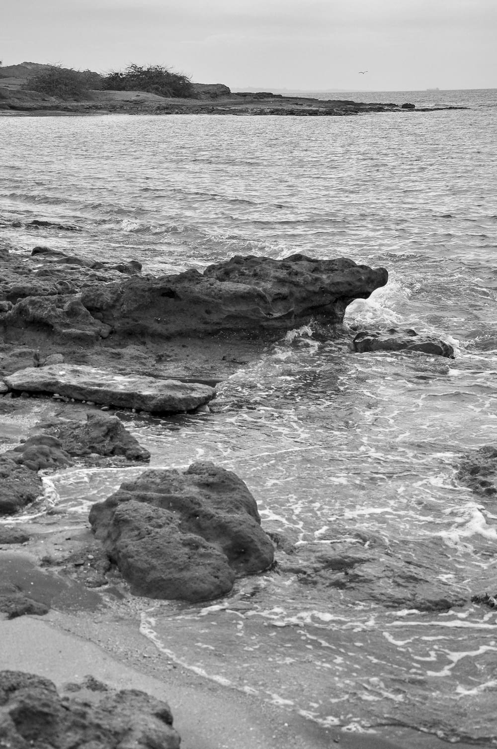 a black and white photo of the ocean and rocks