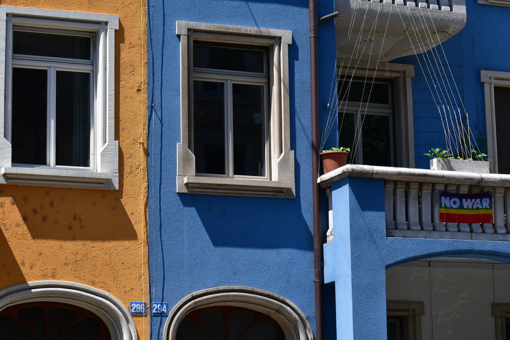 ein blaues Gebäude mit zwei Fenstern und einem Schild an der Seite
