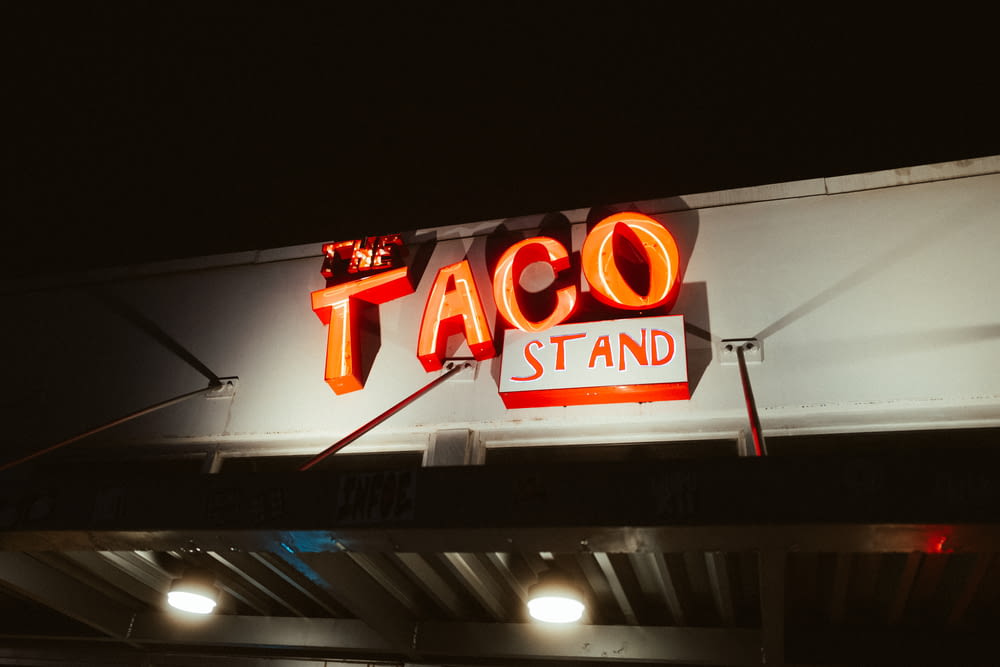 a taco stand sign lit up at night