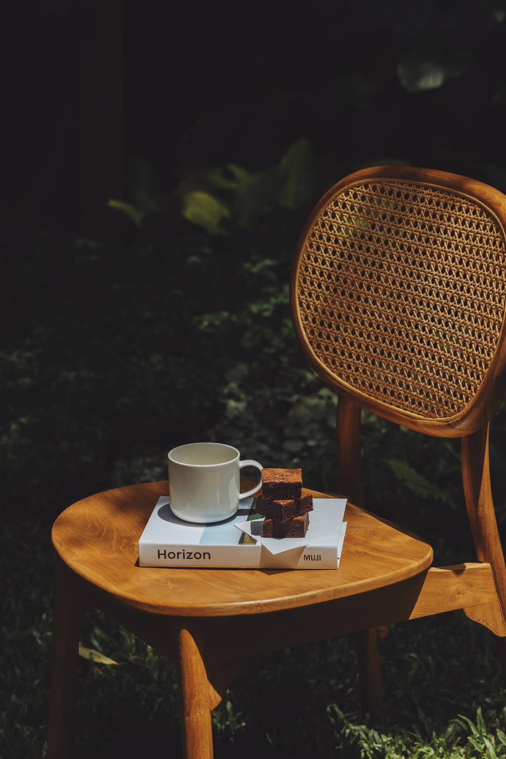 a wooden chair with a book and a cup on it