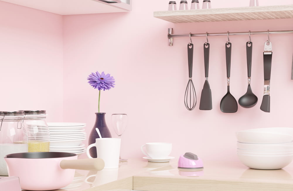 a pink kitchen with utensils hanging on the wall