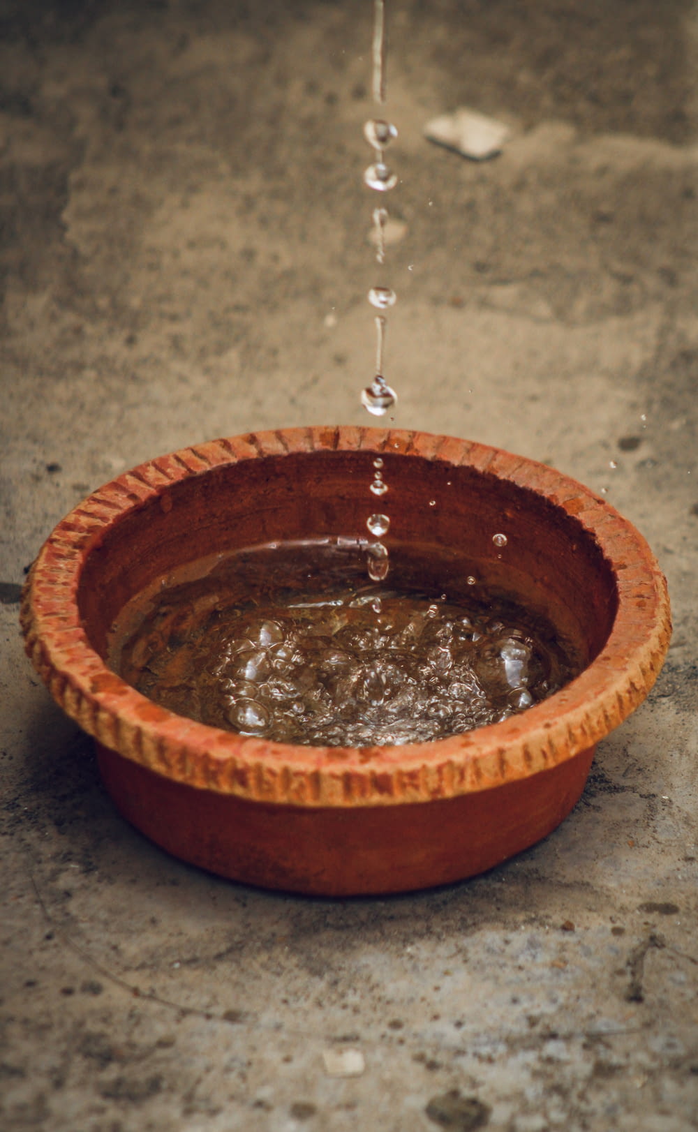 a wooden bowl filled with water on top of a cement floor