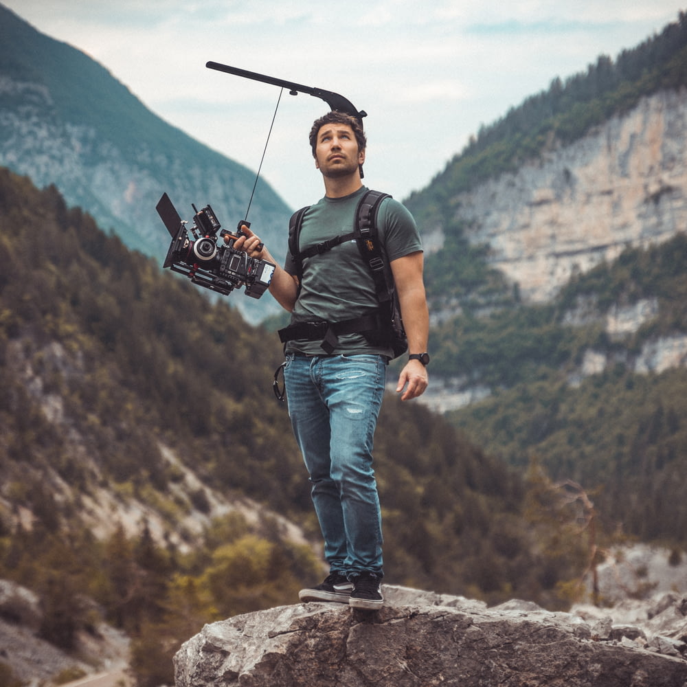 Ein Mann, der eine Kamera auf einem Felsen hält