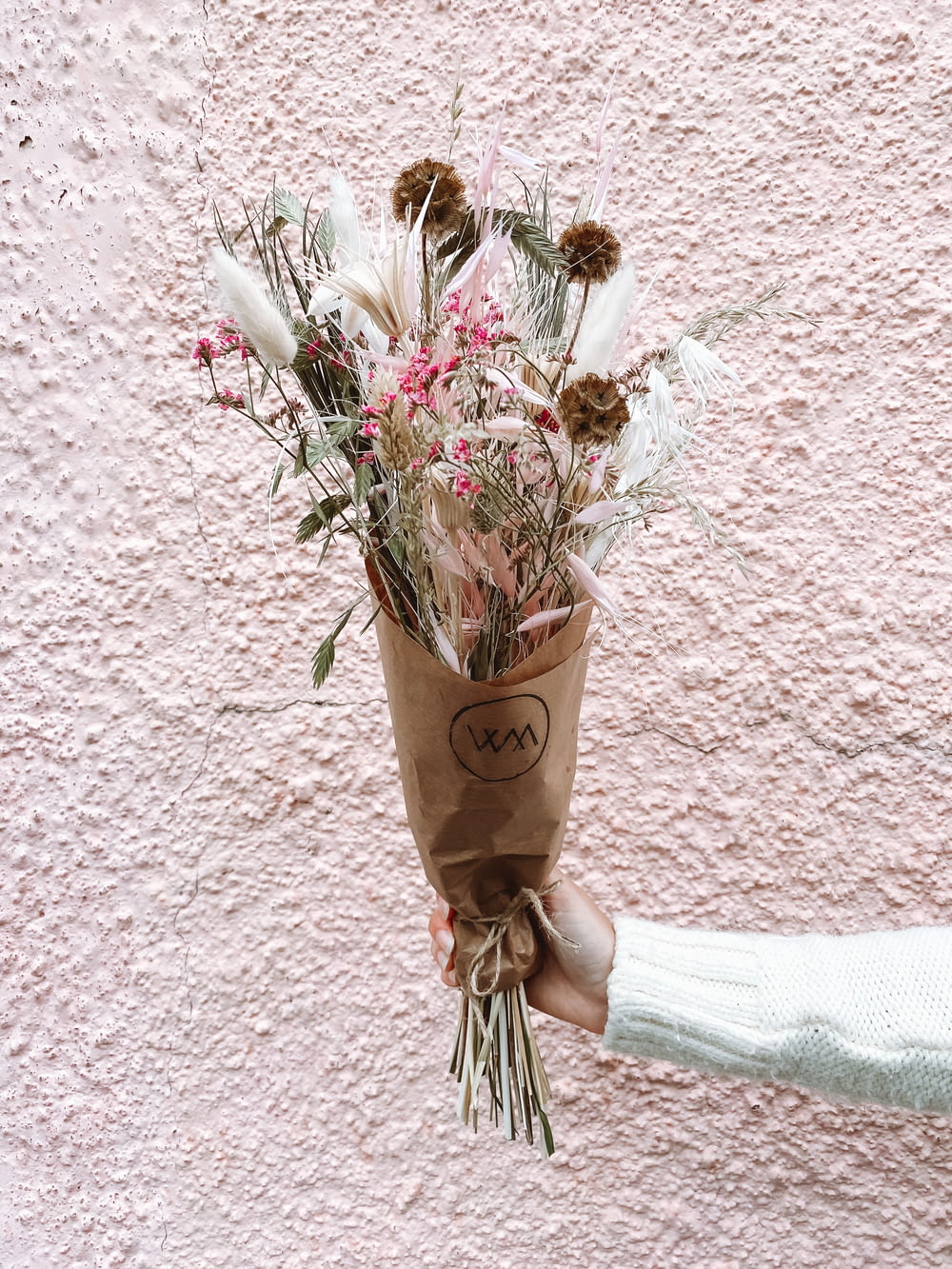 a person holding a paper bag with flowers in it