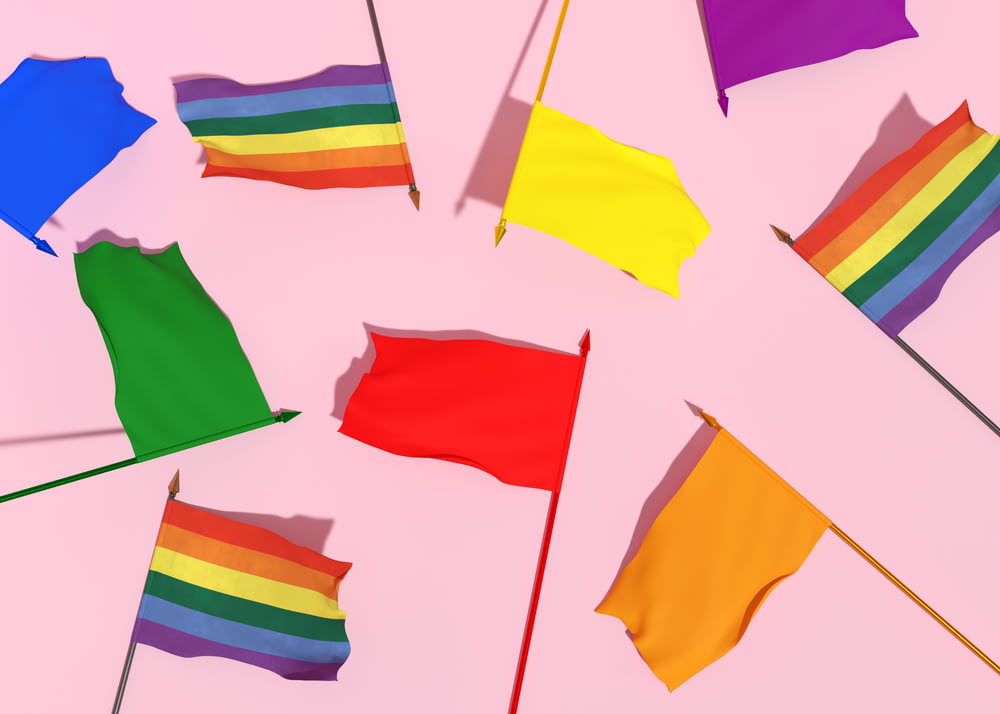 a group of rainbow colored flags on a pink background