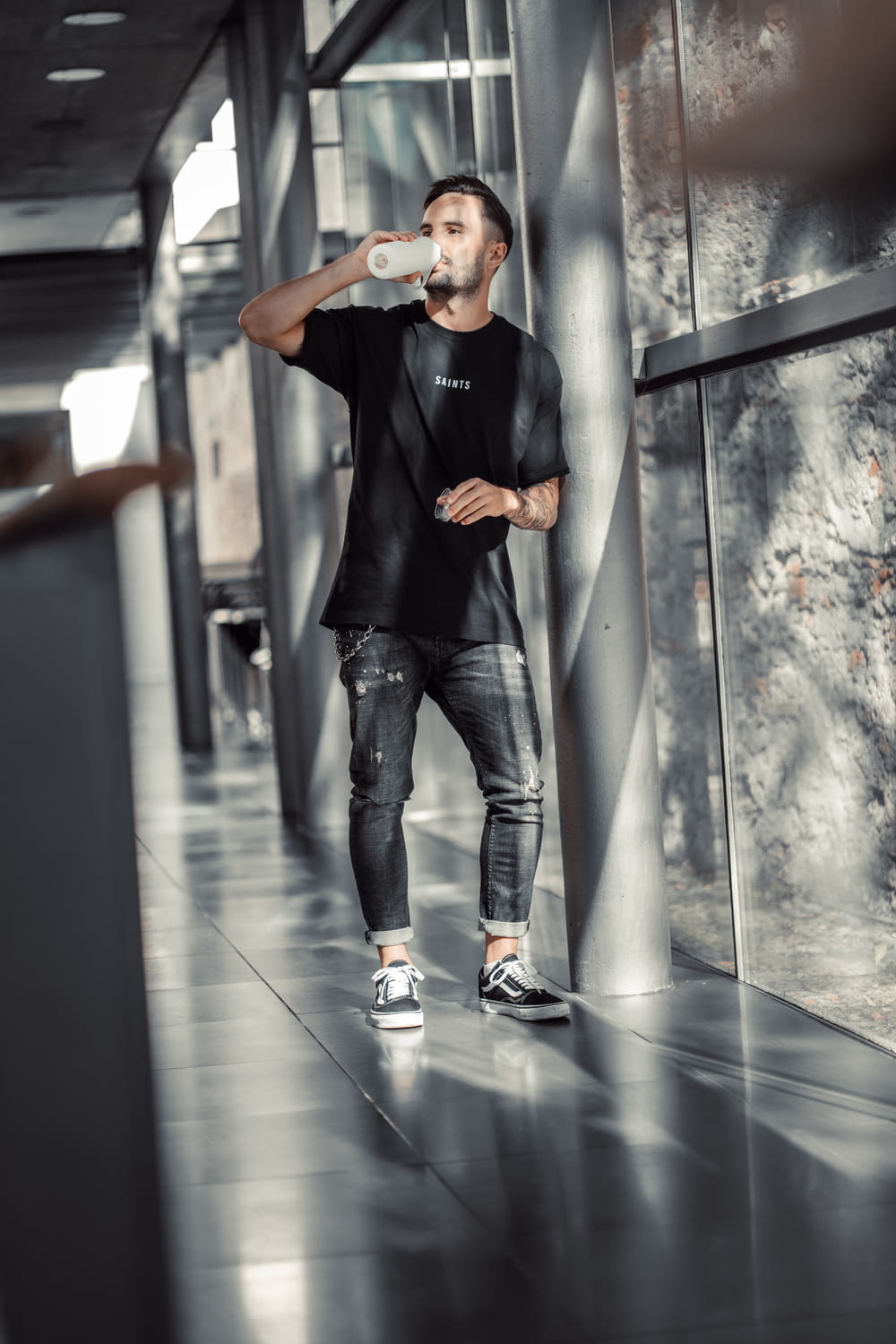 Un hombre parado en un pasillo bebiendo de una botella