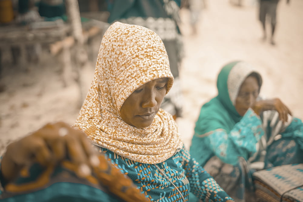 two women sitting on the ground in a village