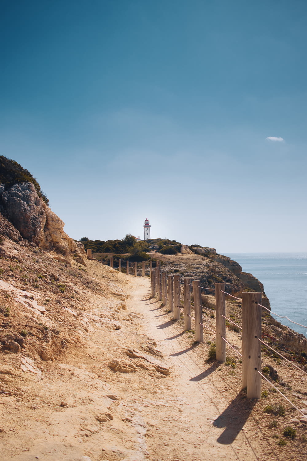 a path leading to a light house on a cliff