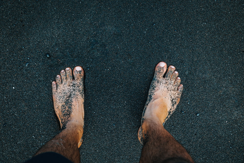 a person standing in the sand with their feet in the sand