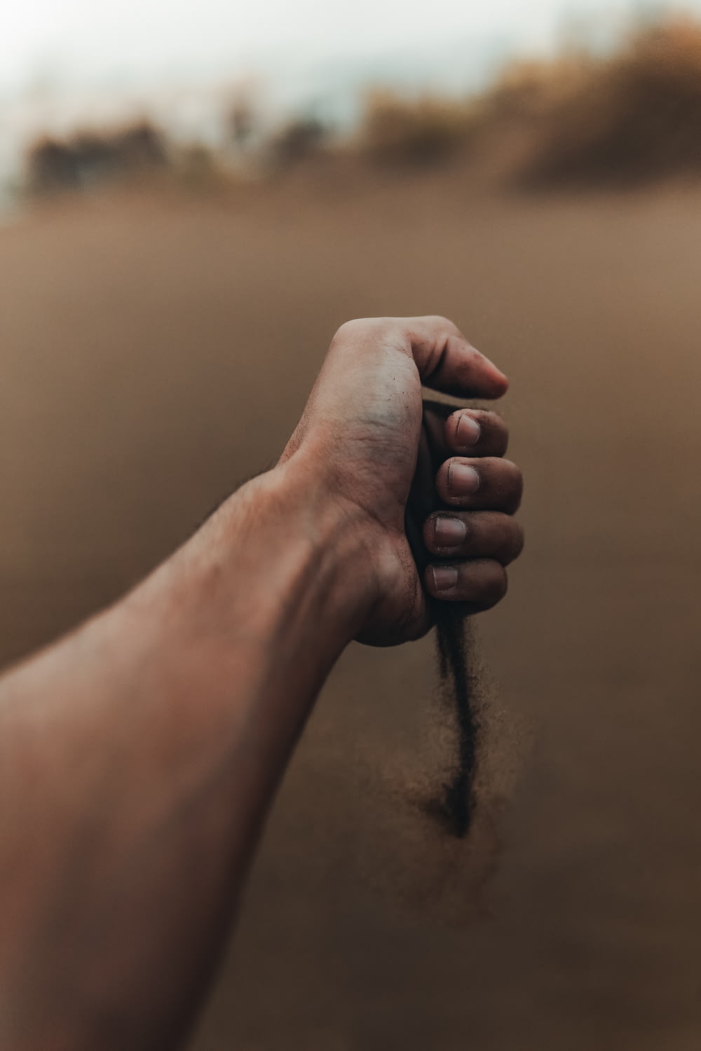 a hand holding a string in the sand