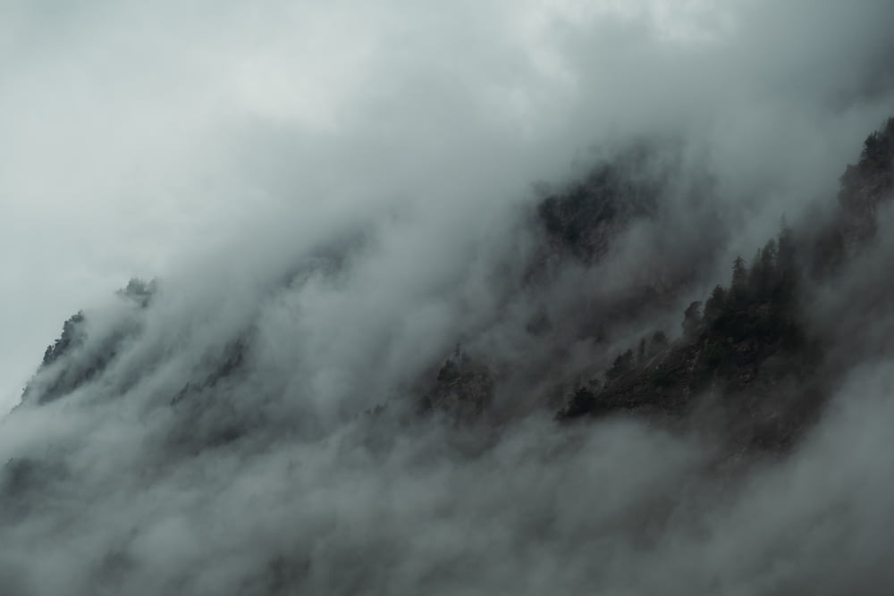 a mountain covered in fog and clouds on a cloudy day