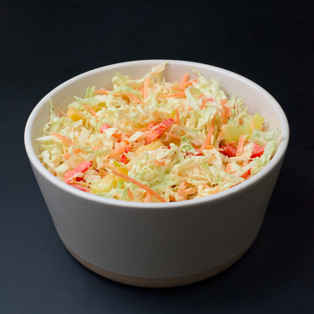 a white bowl filled with coleslaw on top of a table