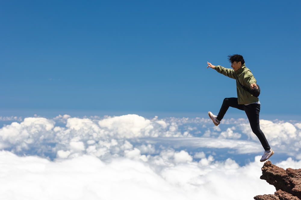 Ein Mann springt von einer Klippe in den Himmel