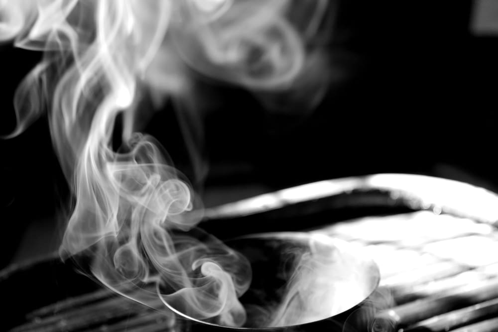 a black and white photo of a spoon with smoke coming out of it