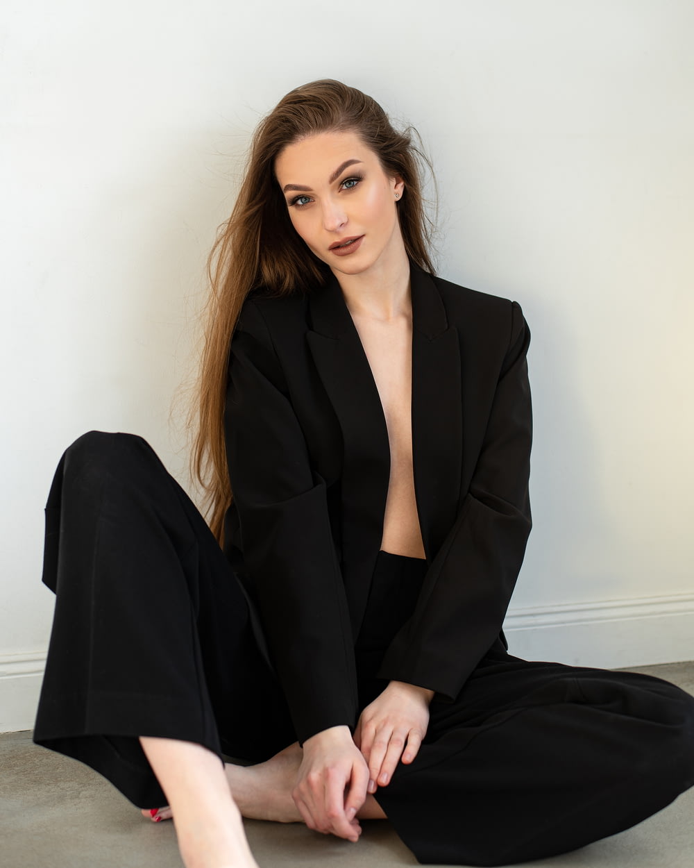 a woman in a black suit sitting on the floor
