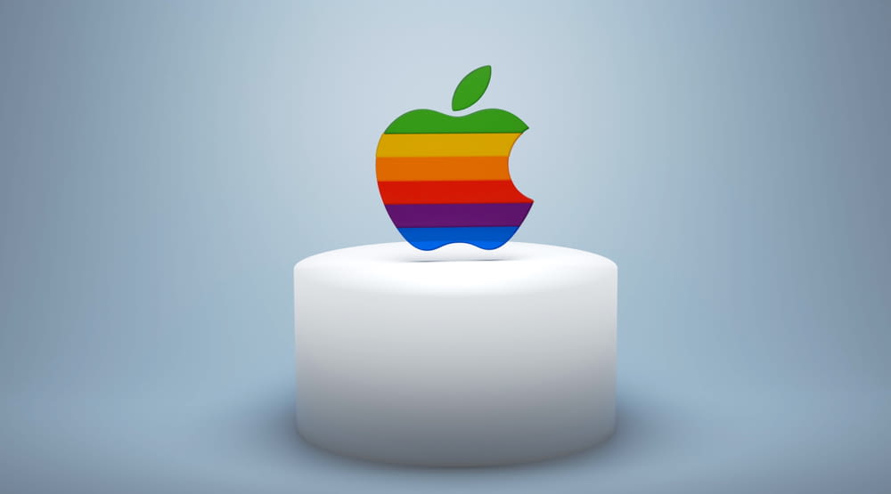 a rainbow apple sitting on top of a white cake