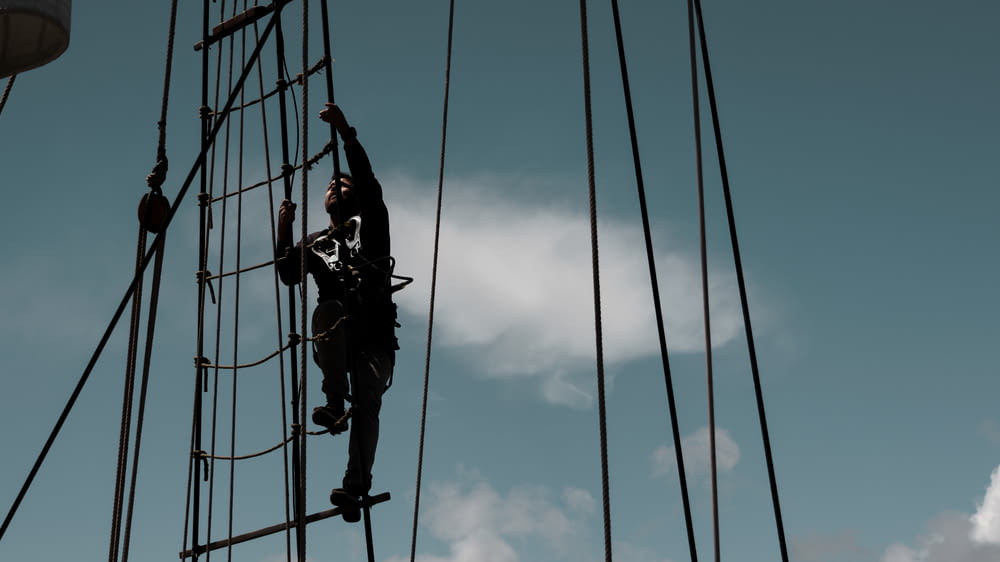 a man climbing up the side of a tall ship