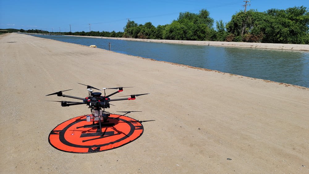 a remote controlled helicopter sitting on the side of a river
