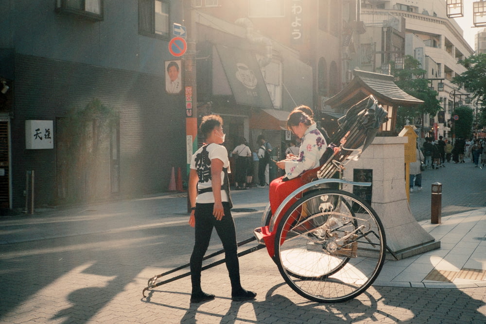 two people walking down a street next to a bike