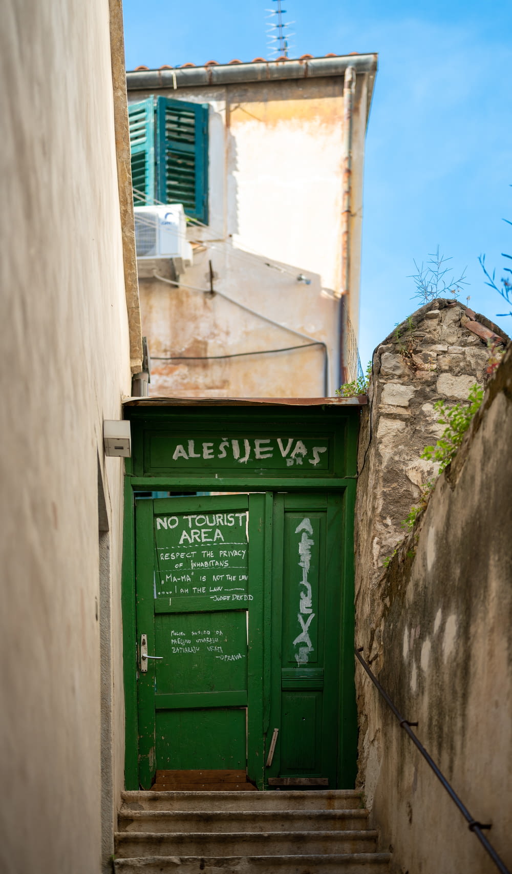 an alleyway with a green door and stairs
