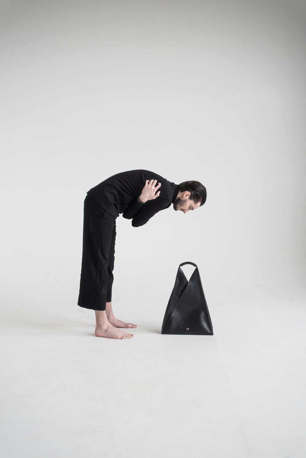 a woman bending over a black bag on a white background