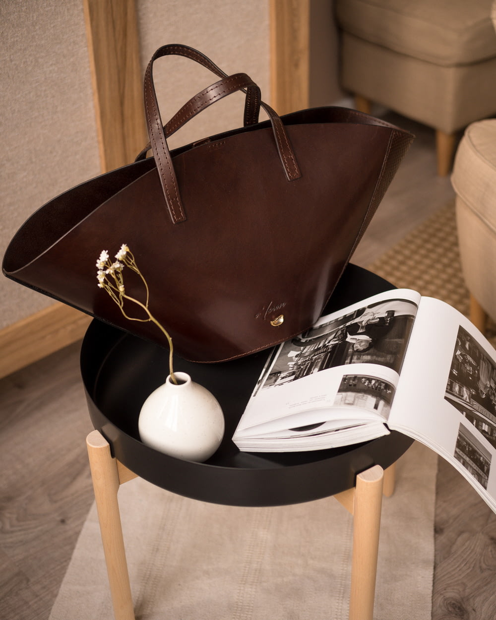 a brown purse sitting on top of a table next to an open book