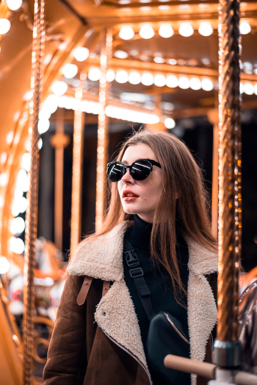 a woman wearing sunglasses standing in front of a merry go round