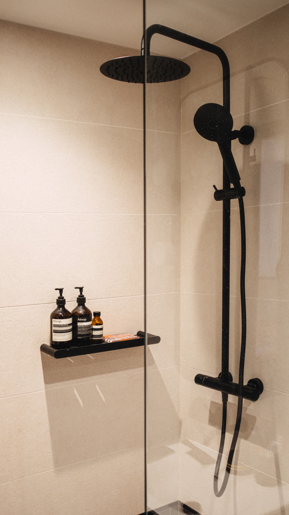 a shower with a black shower head and shower faucet