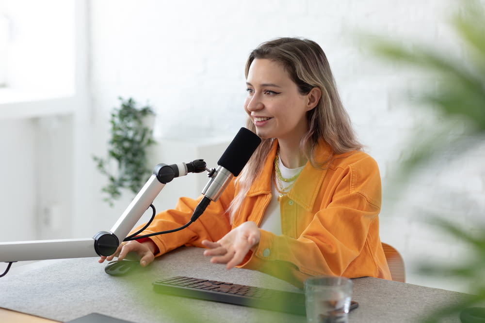 a woman sitting at a table with a microphone and a laptop