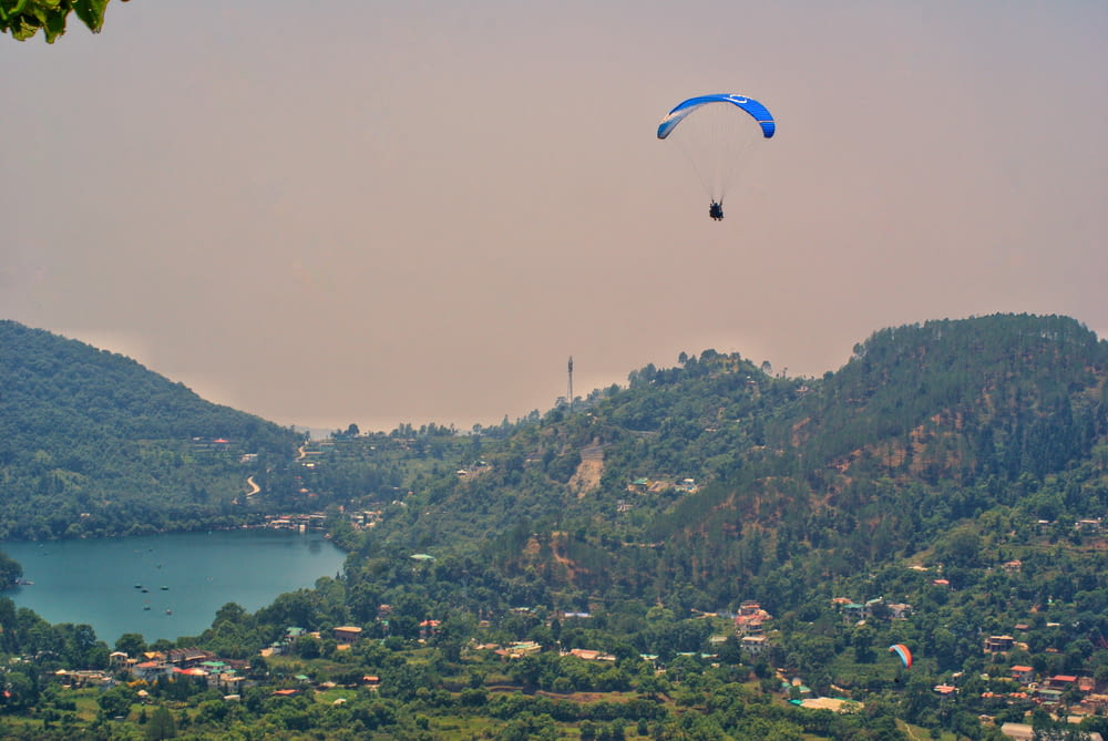 a couple people parachuting over a town by a lake