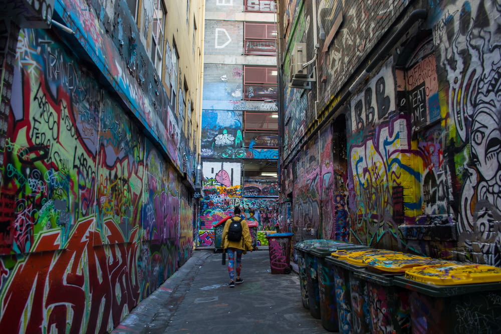 a person walking in a alley with graffiti on the walls