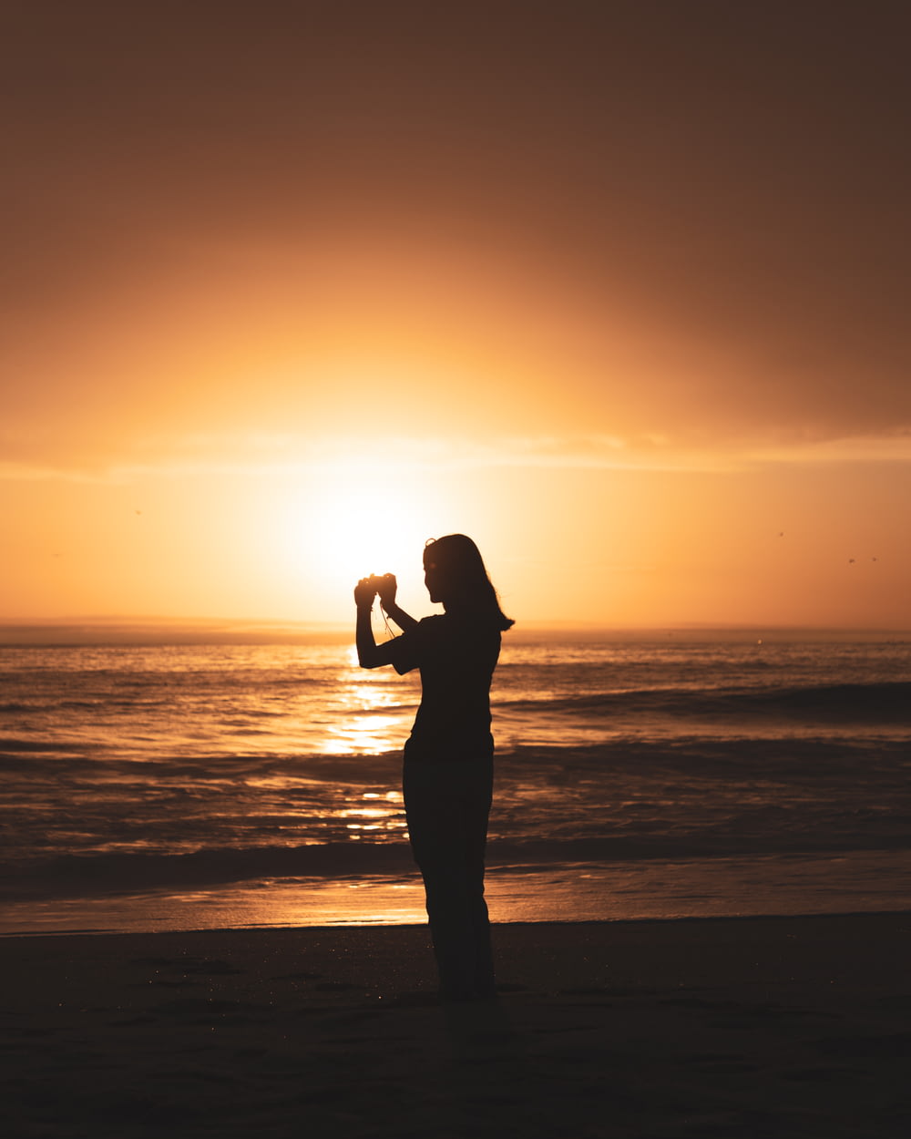 a person holding a baby on a beach at sunset
